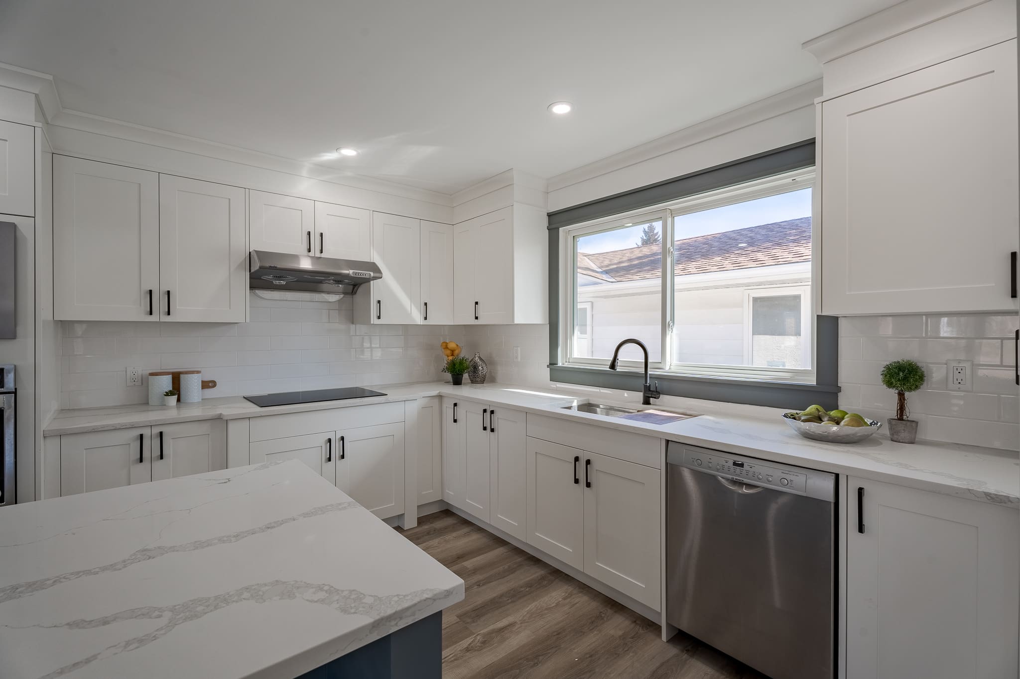 A kitchen with white cabinets and a window.