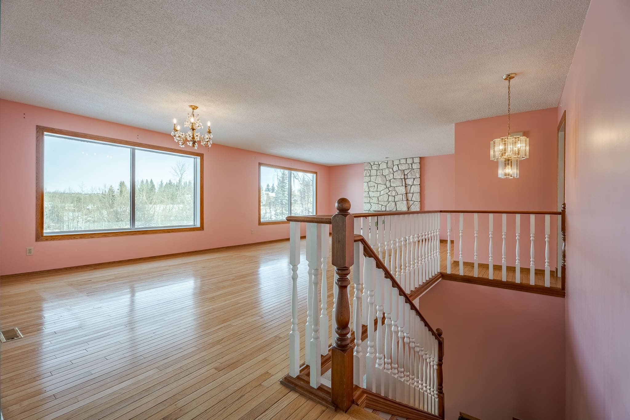 A large open room with pink walls and wooden floors.