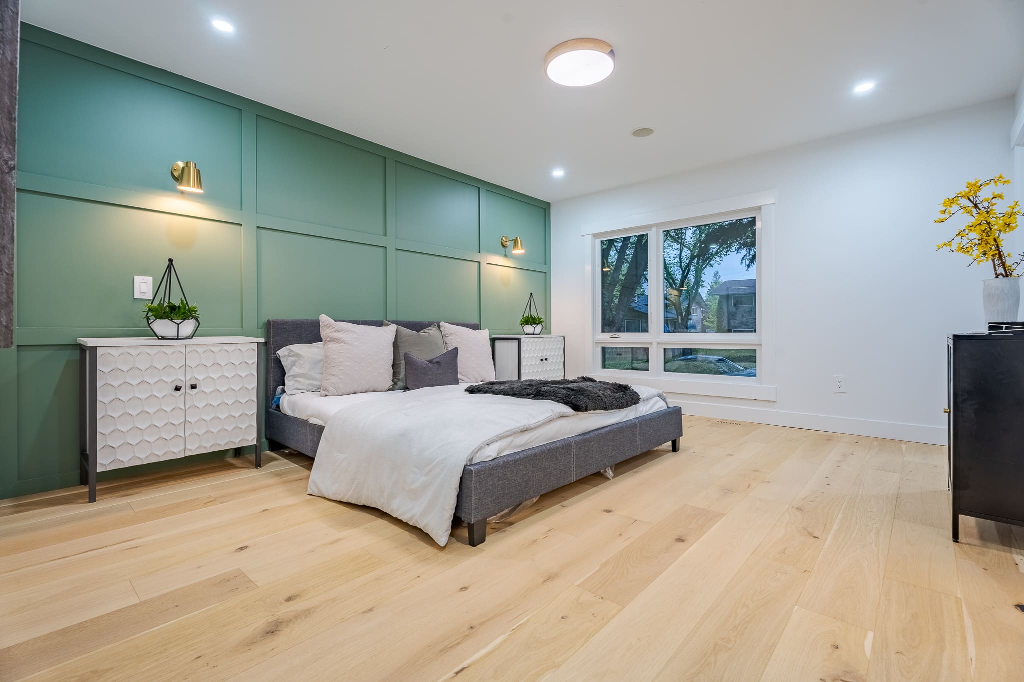 A bedroom with a bed, nightstands and window.