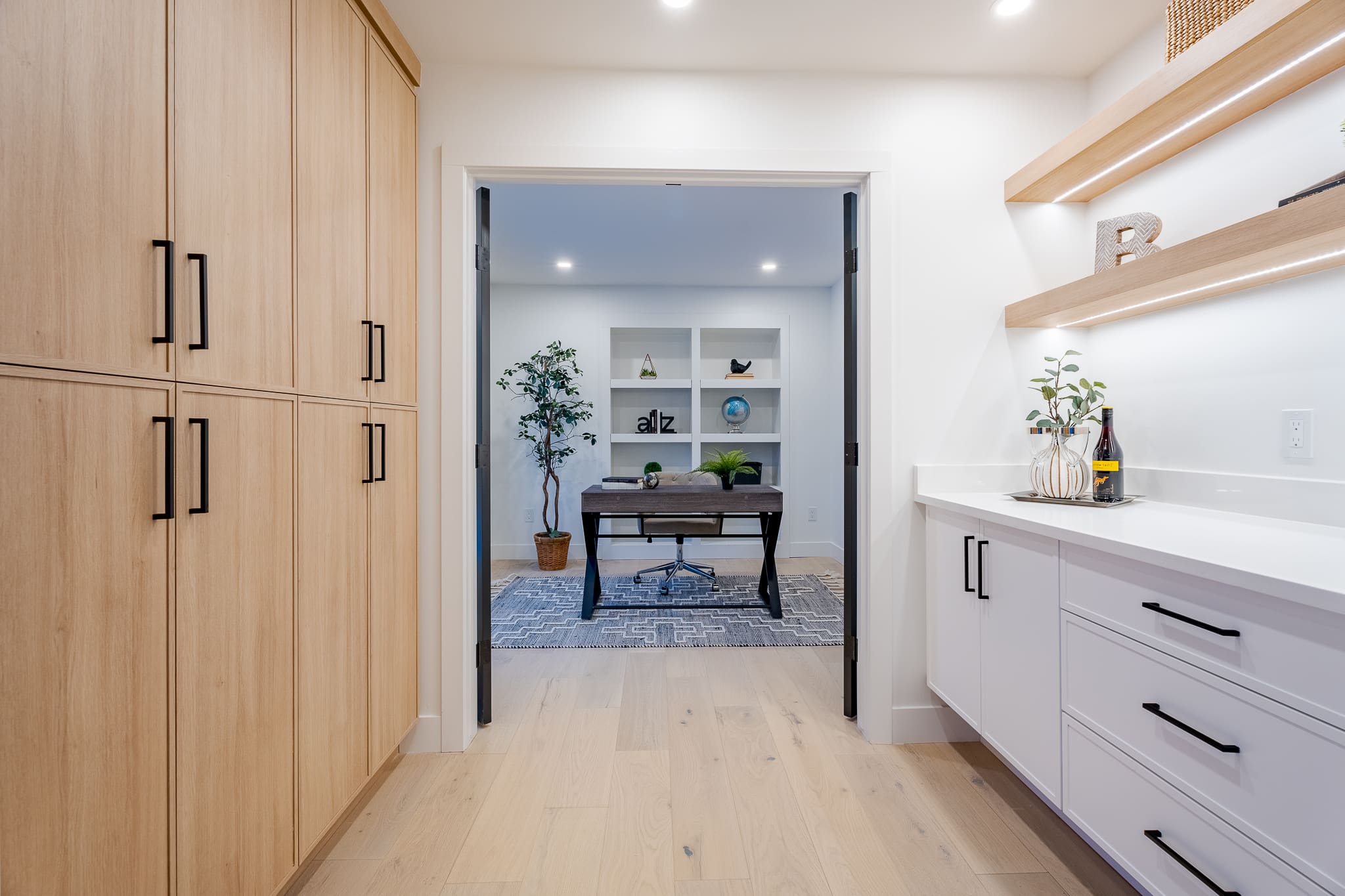 A kitchen with white cabinets and wood floors.