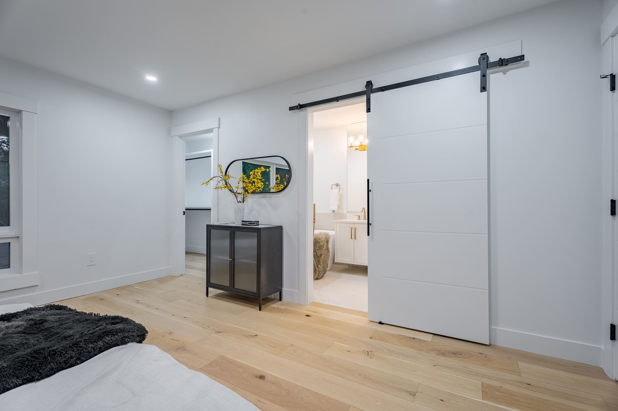 A bedroom with white walls and wooden floors.