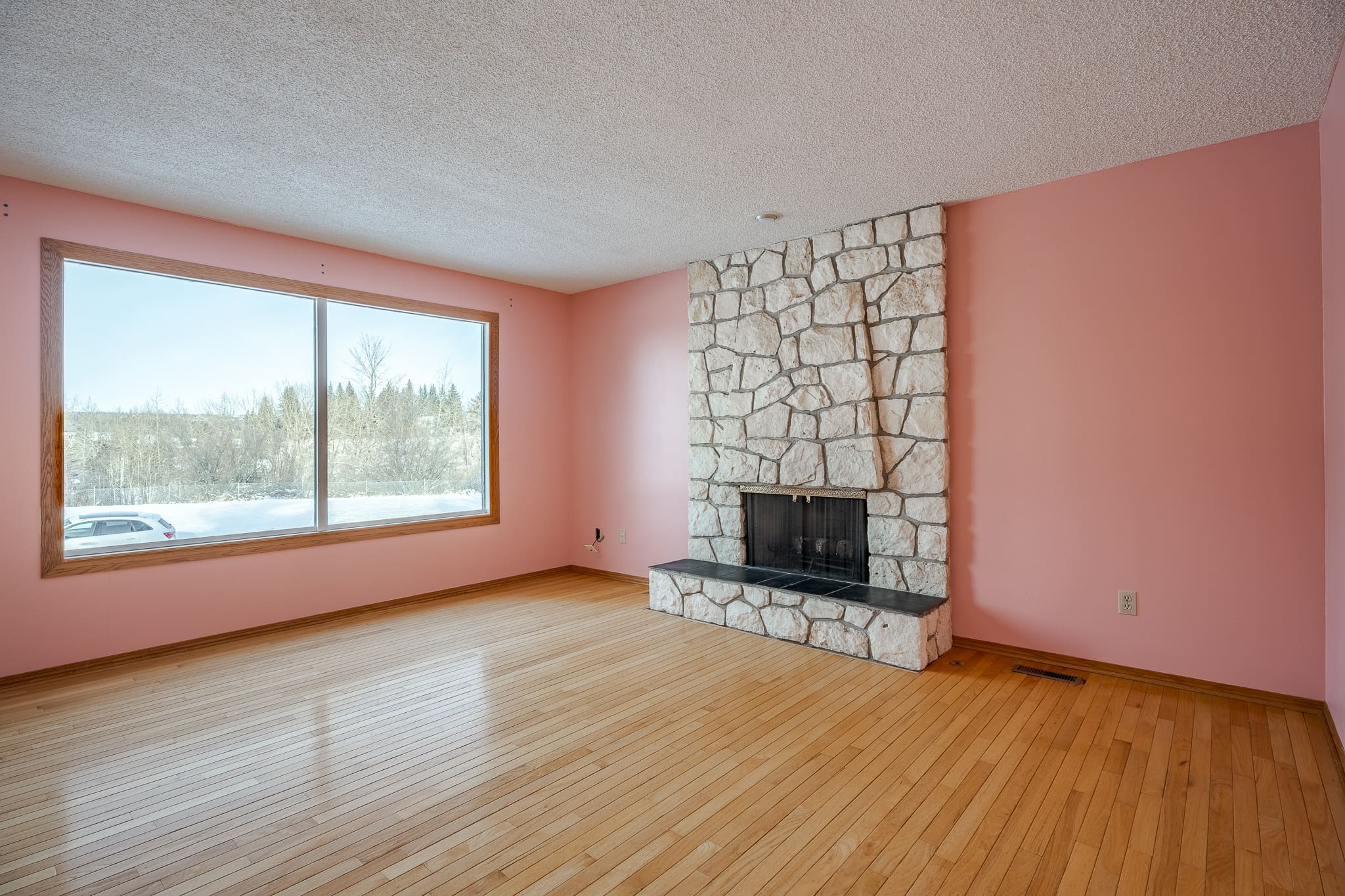 A living room with hard wood floors and a stone fireplace.