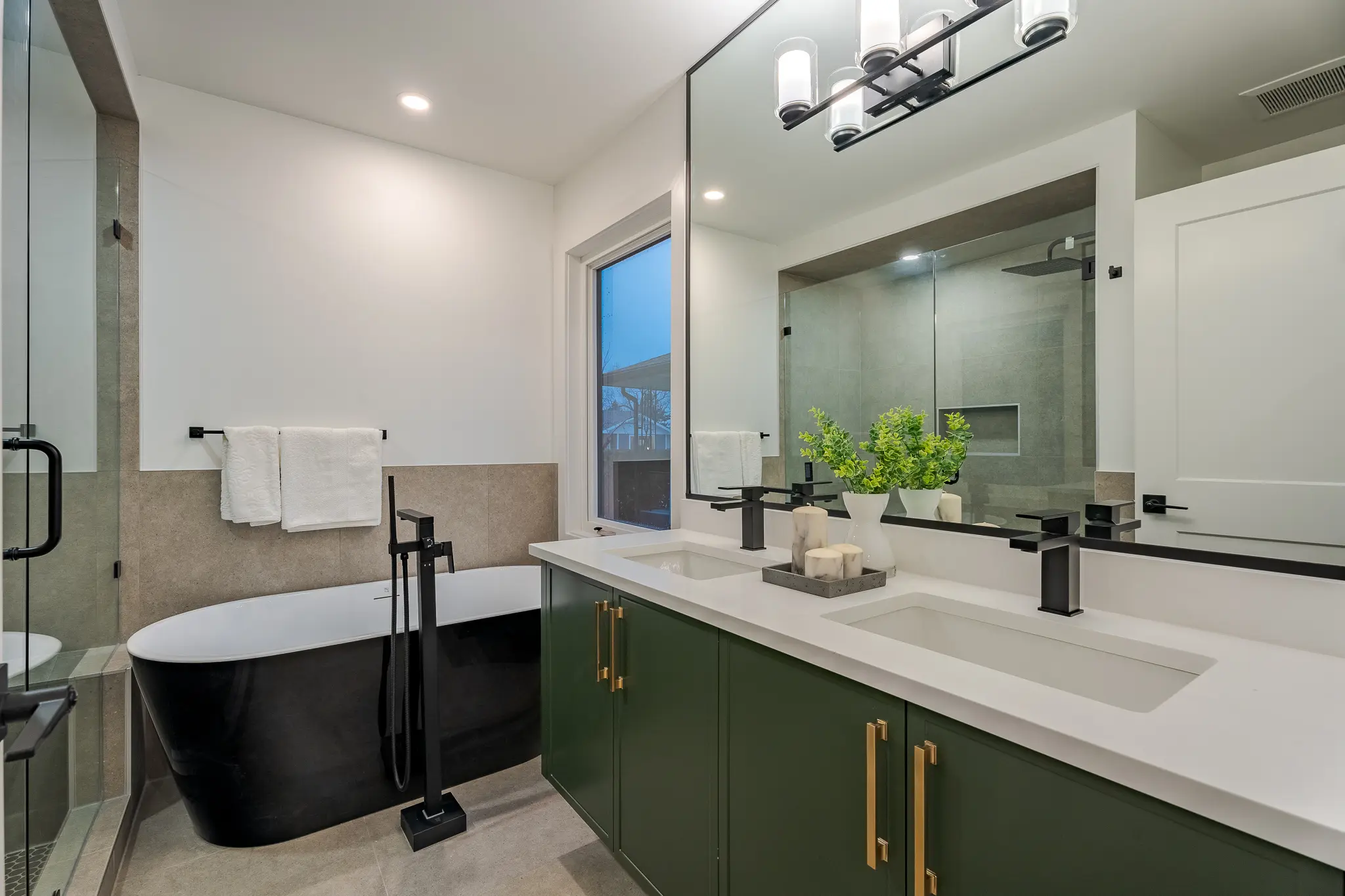 A bathroom with green cabinets and white counter tops.