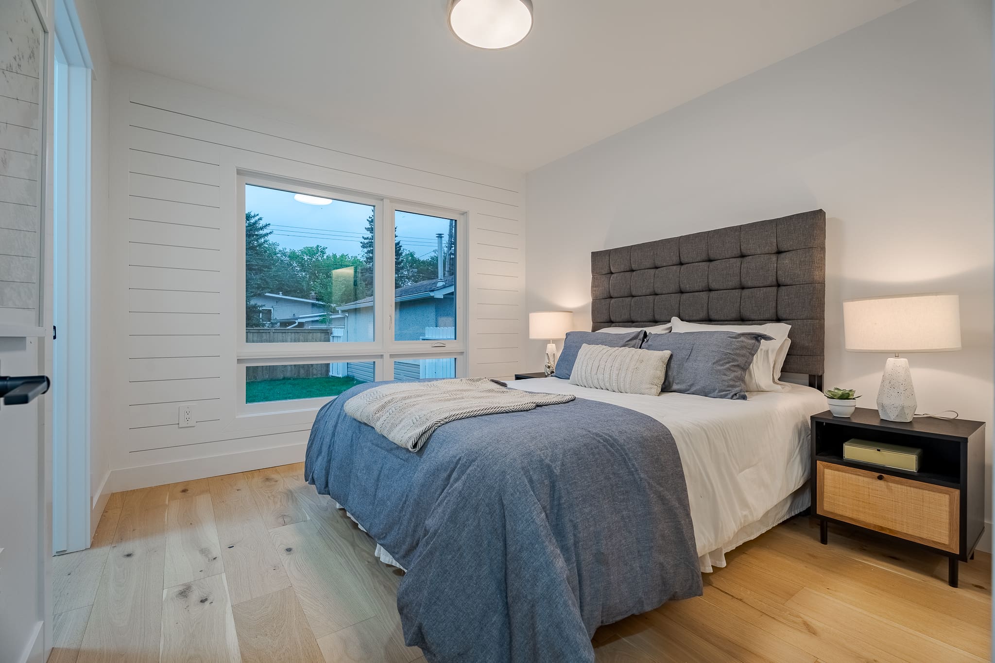 A bedroom with a bed, nightstand and window.