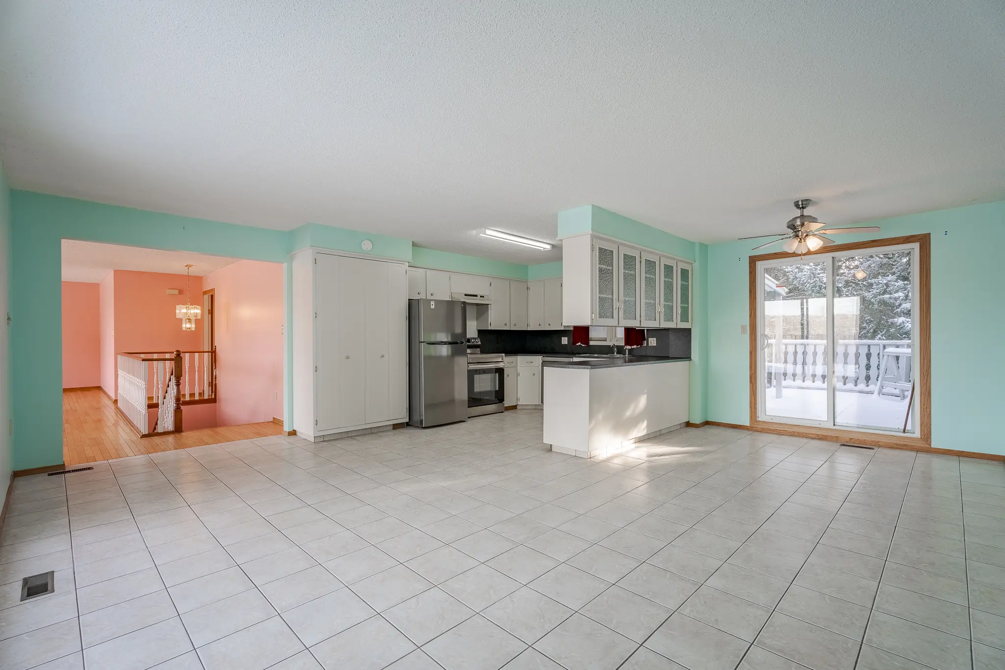 A kitchen with white tile floors and green walls.