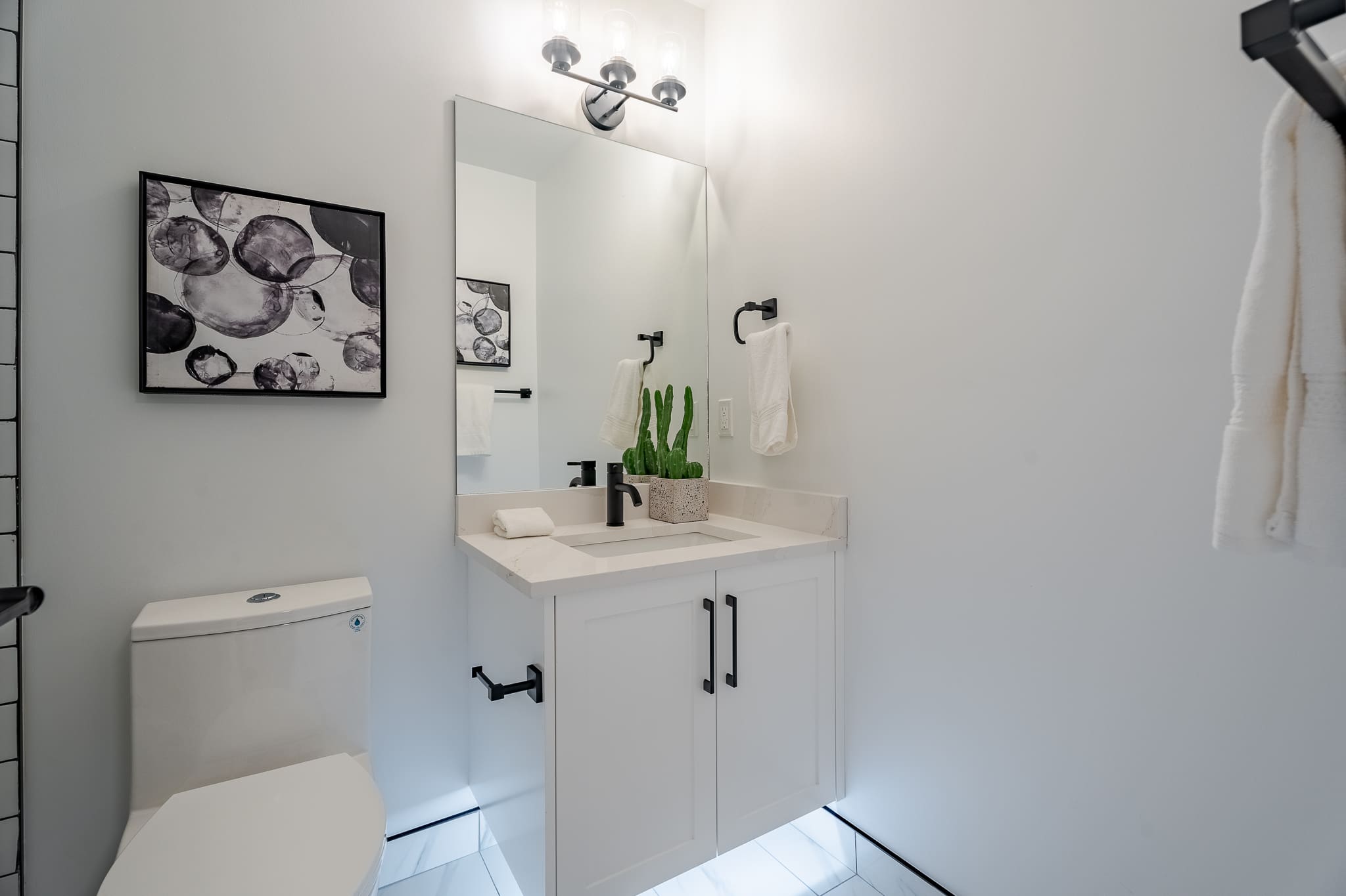 A bathroom with white walls and a large mirror.