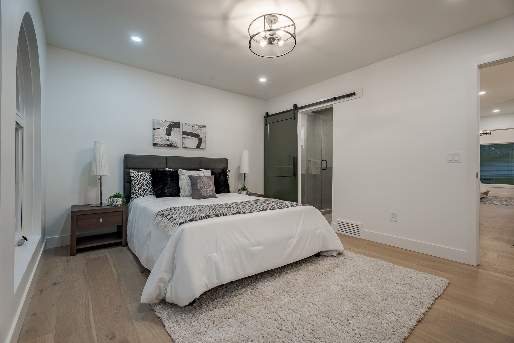 A bedroom with a bed, nightstand and sliding door.