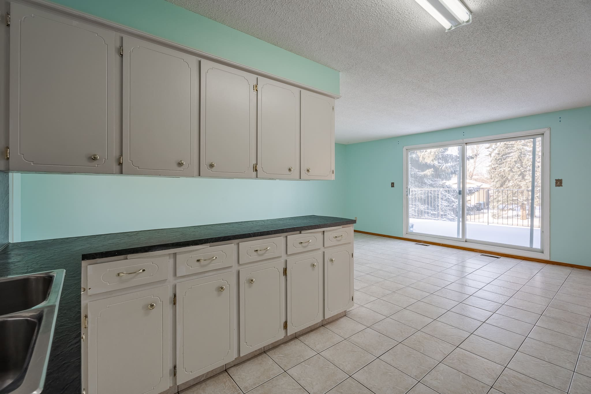 A kitchen with white cabinets and green walls.