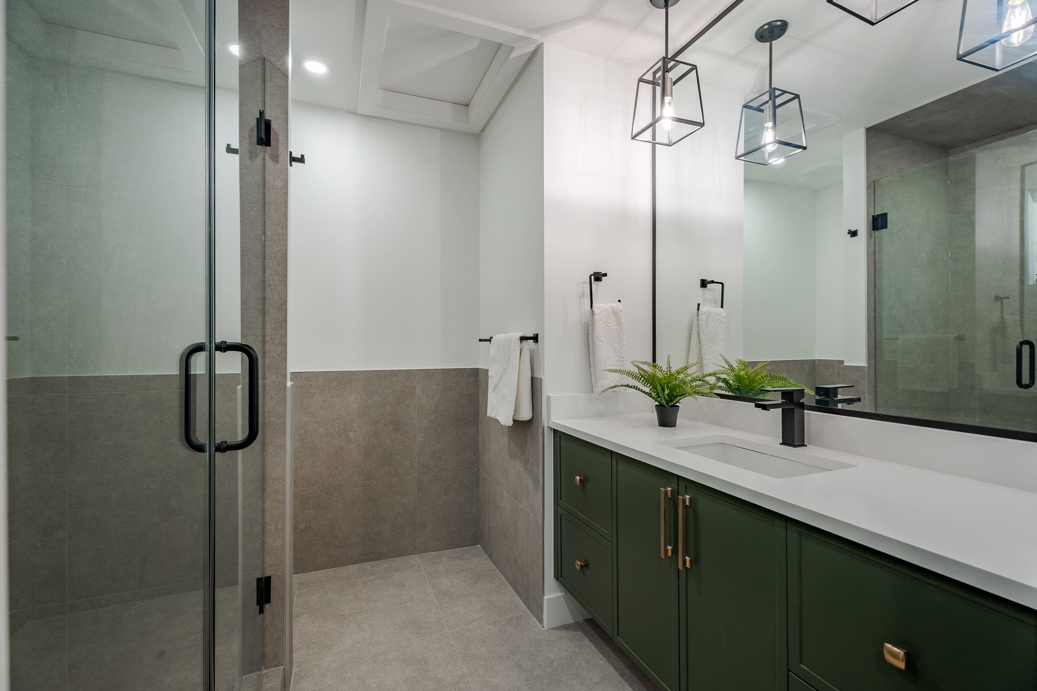 A bathroom with green cabinets and white counter tops.