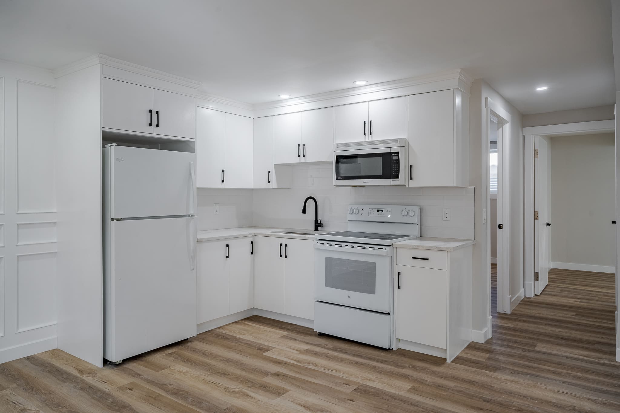 A kitchen with white cabinets and appliances in it