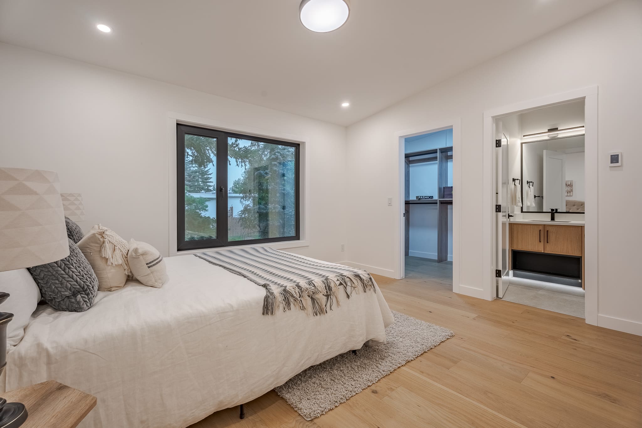 A bedroom with a bed, window and wooden floors.