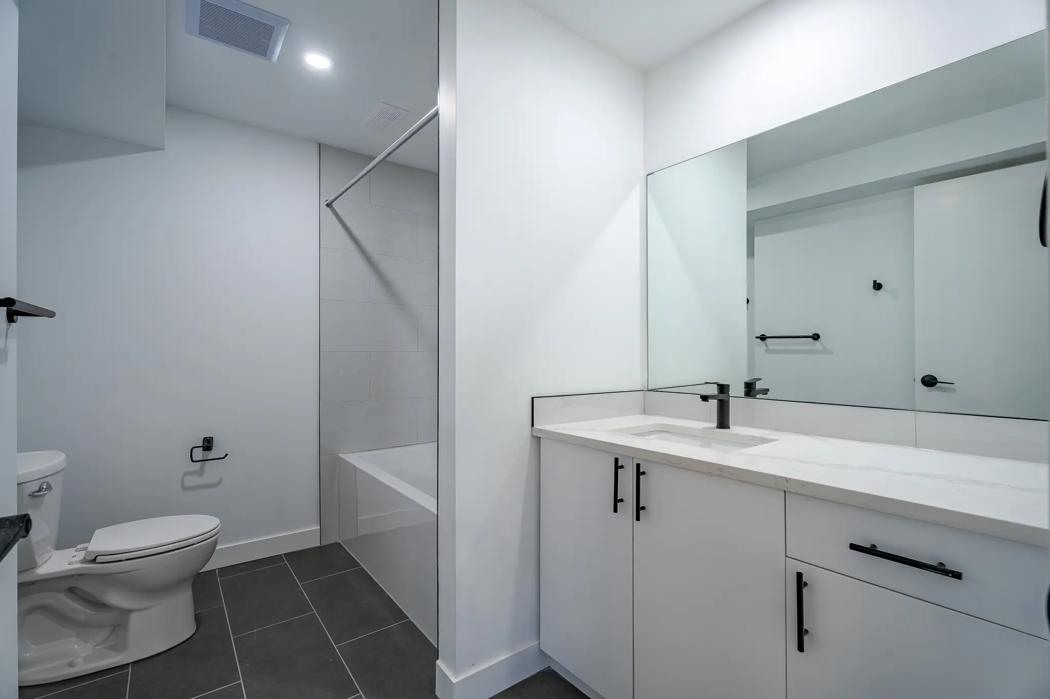 A bathroom with white cabinets and a tub.