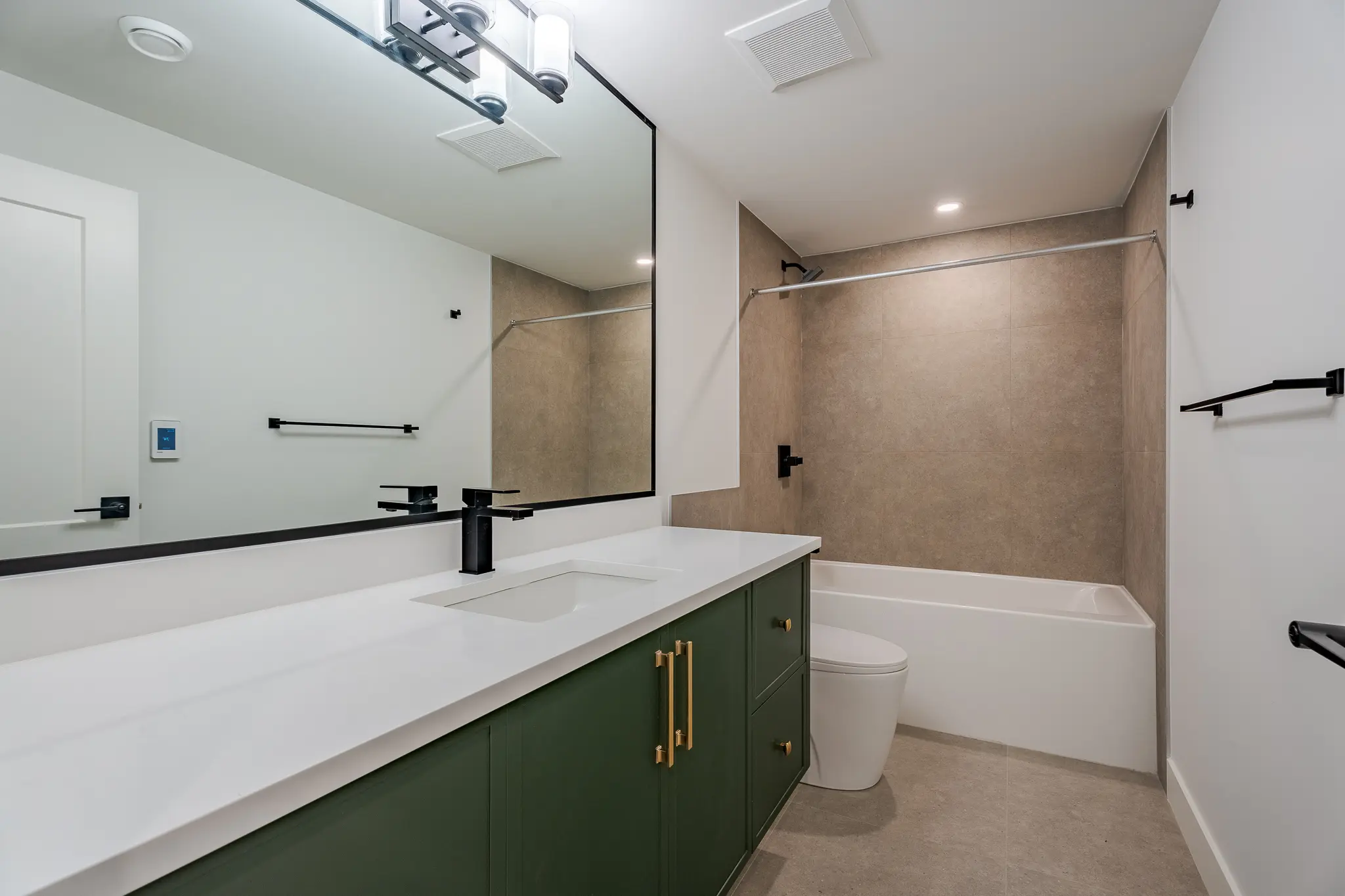 A bathroom with green cabinets and white fixtures.