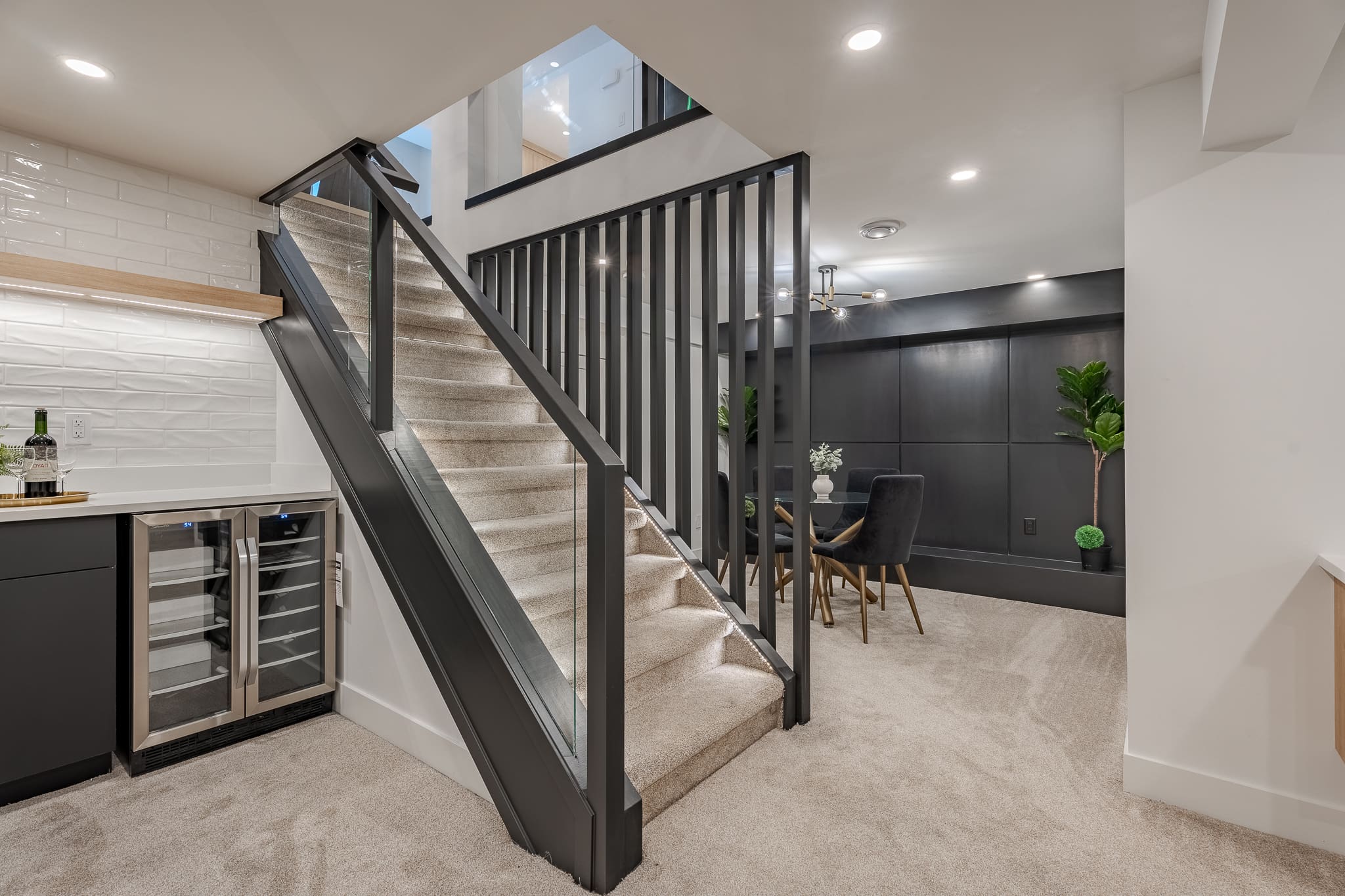 A staircase with glass railing and black wood handrail.