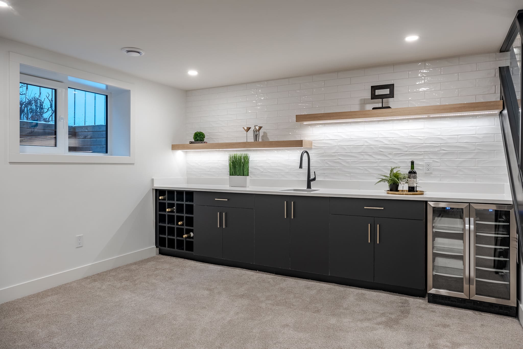 A kitchen with white walls and black cabinets.