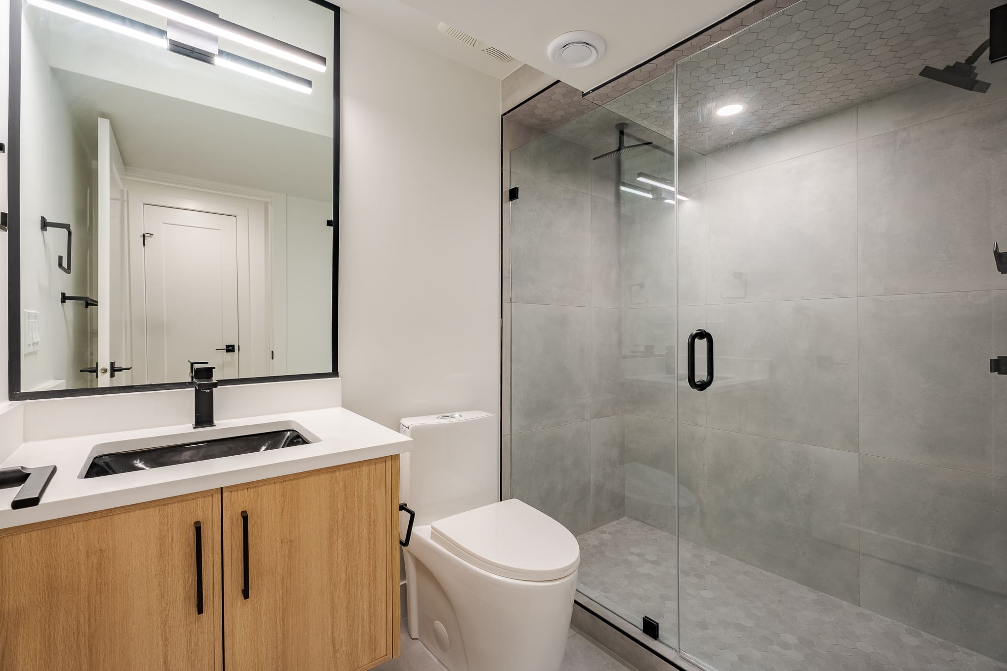 A bathroom with a toilet, sink and shower.