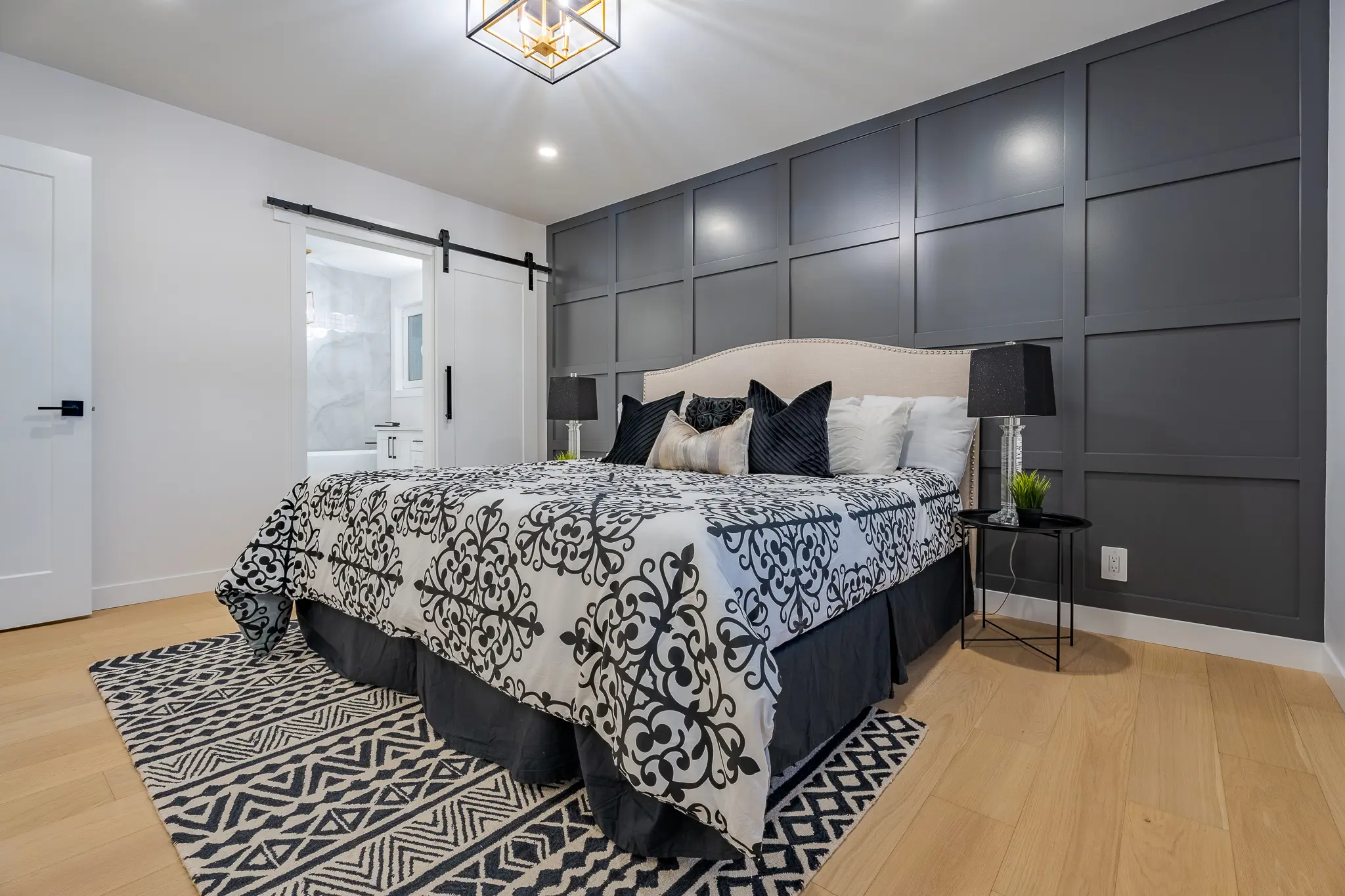 A bedroom with black and white bedding, a bed, and a wall.