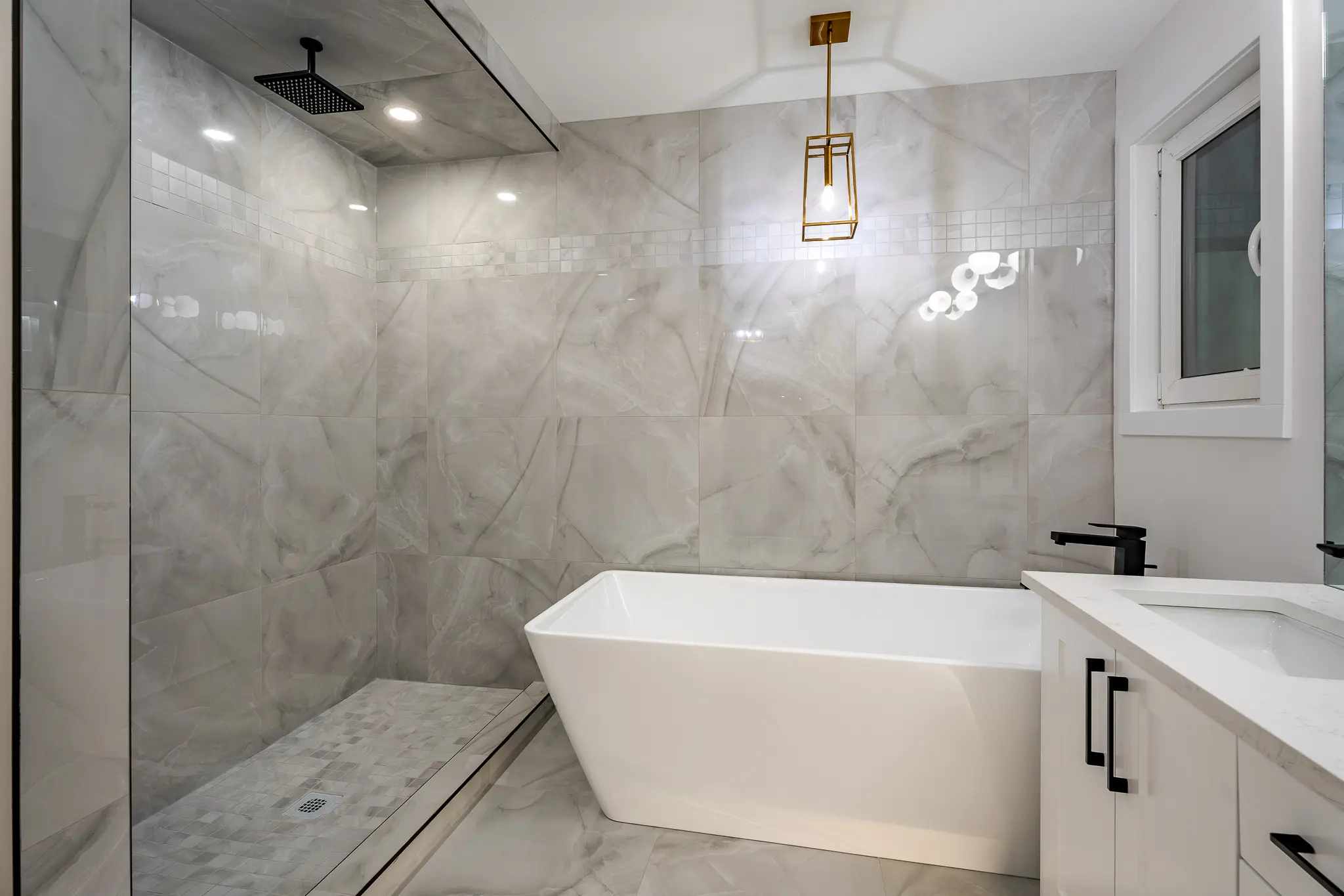 A bathroom with marble walls and floors, a tub and shower.