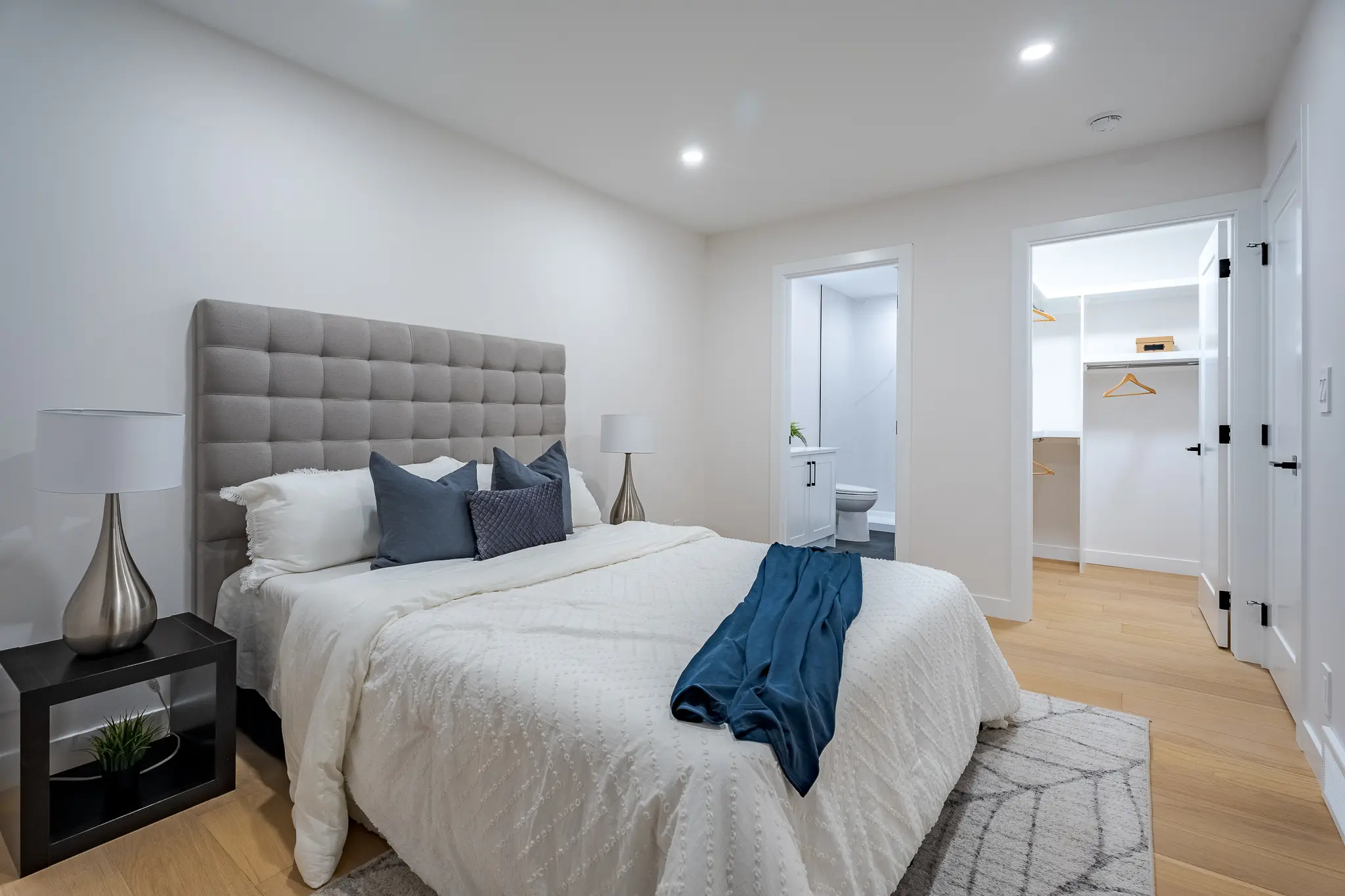 A bedroom with a bed, pillows and a rug.