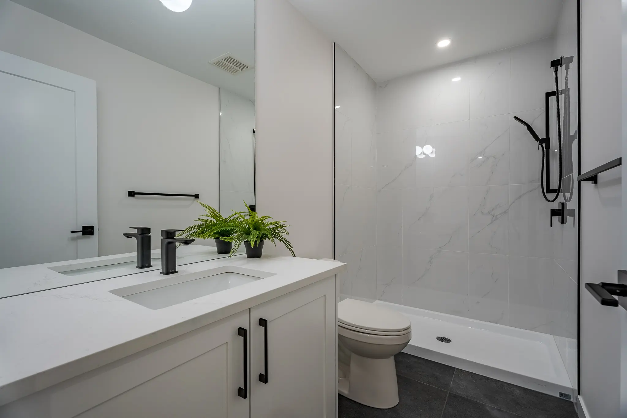 A bathroom with white walls and black accents.