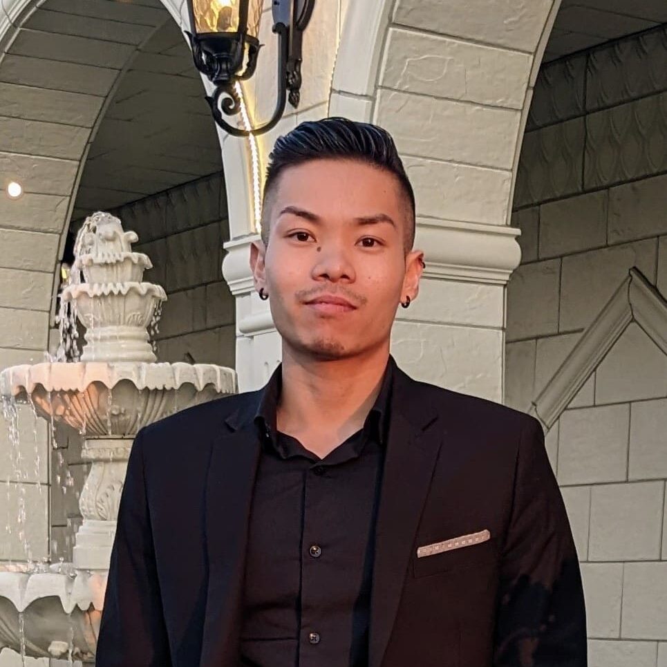 A man in black jacket standing next to fountain.