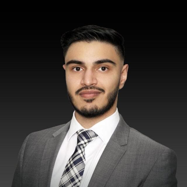 A man in a suit and tie standing up against a black background.